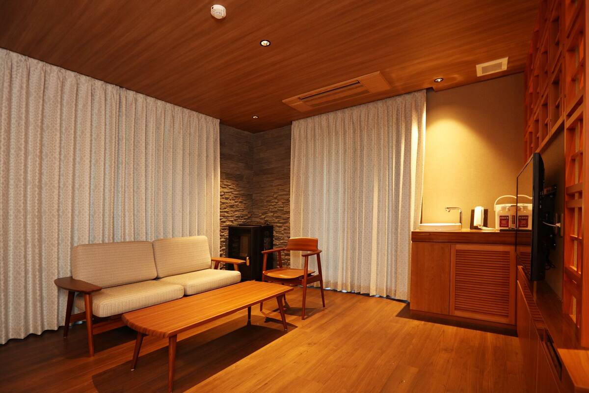 A cozy living room with a sofa, a wooden coffee table, and a fireplace.