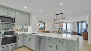 A modern kitchen with light blue cabinets, stainless steel appliances, and a large island.