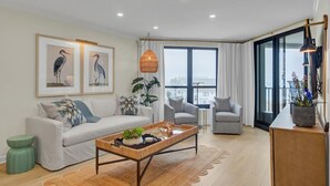 A modern living room with a sofa, armchairs, a coffee table, and framed artwork on the wall.