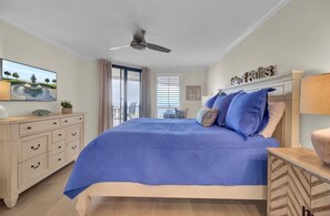 A bedroom with a bed, a ceiling fan, a dresser, a painting, and a window with blinds. - Fully Renovated 2025 | Oceanfront 2BR in Wild Dunes (Isle of Palms)
