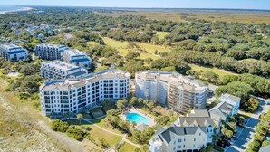 A resort with multiple buildings, a swimming pool, and surrounding greenery.