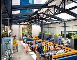 Un restaurante moderno con techos altos, paredes de vidrio y diversas opciones de asientos, incluyendo cabinas y mesas.