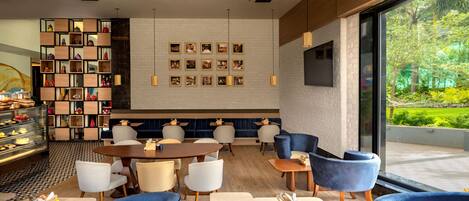 A modern interior with a central seating area, a dessert display, and a wall of framed photos.