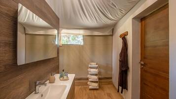 Un baño moderno con piso de madera, un lavamanos blanco, un espejo y un perchero para toallas.