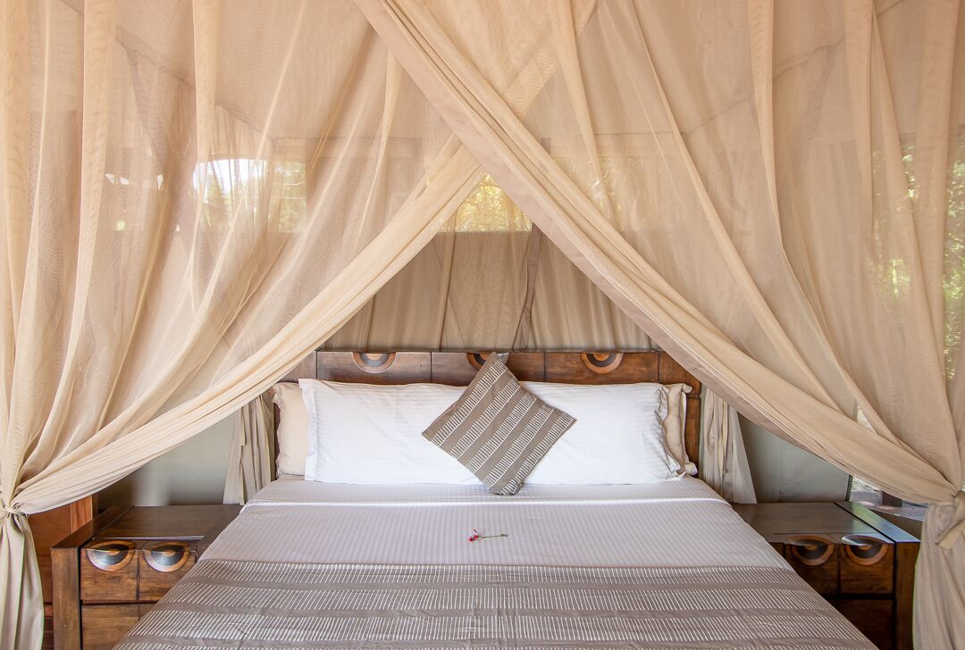 A bed with a canopy, wooden headboard, and two bedside tables.