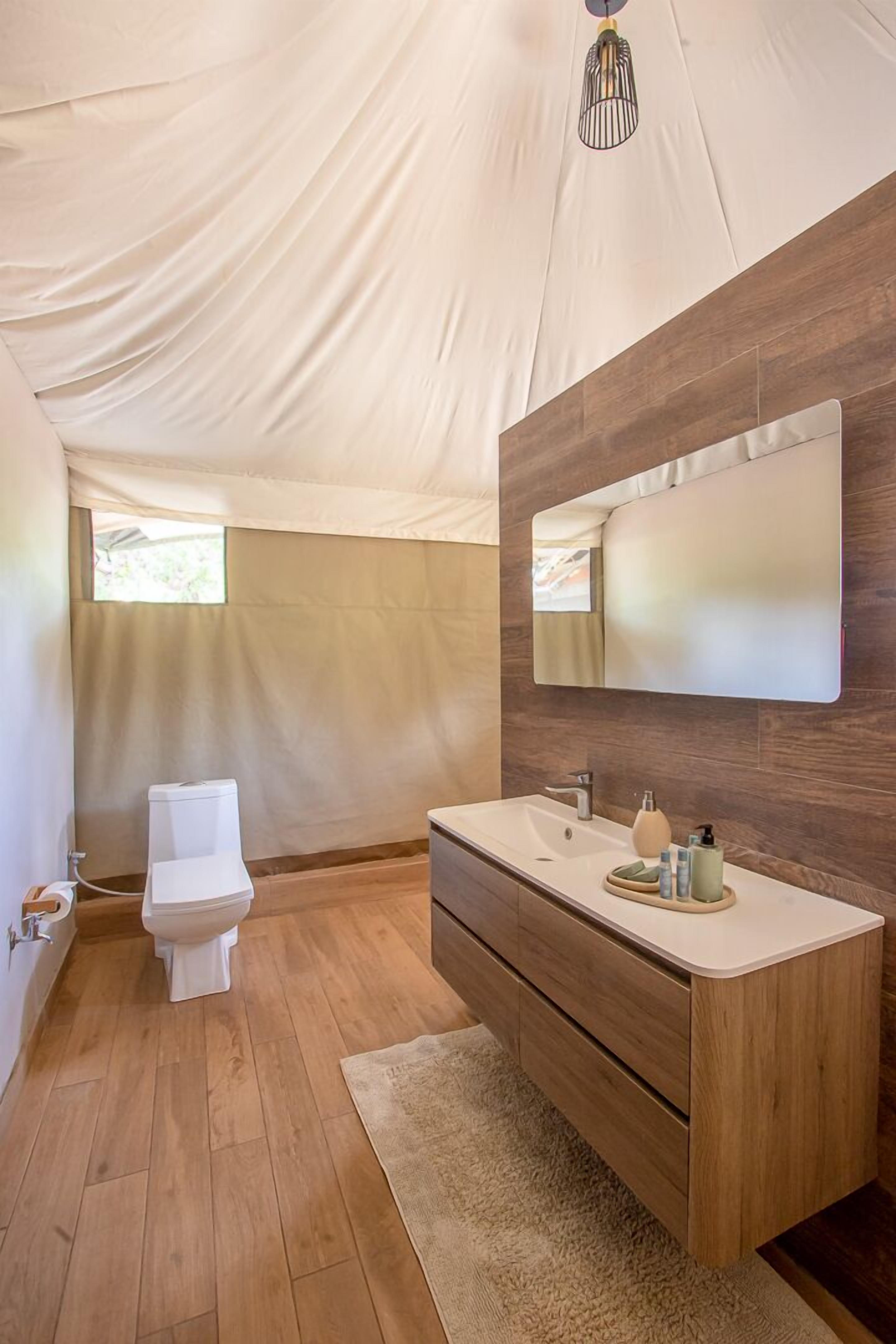A modern bathroom with a wooden vanity, a large mirror, and a toilet.