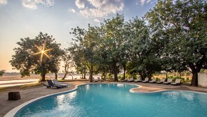 A swimming pool with lounge chairs and trees around it. - Mopani Safari Lodge (South Luangwa National Park)