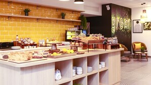 A breakfast bar with various food items and a coffee station. There are shelves with kitchenware and a refrigerator in the background. - Appart Hotel Odalys City Angers Centre Gare (Angers)