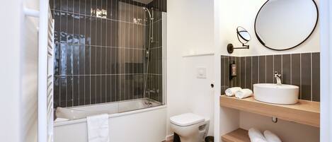 A bathroom with a bathtub, toilet, and a vanity with a sink and mirror.