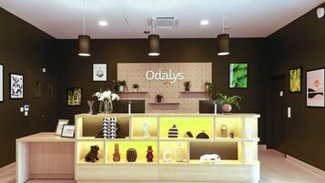 A reception desk with a sign reading "Odalys city" and a modern, minimalist design with shelves displaying various decorative items.