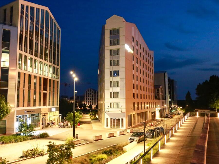 Un edificio moderno con diversi piani, ampie finestre e una zona d'ingresso ben illuminata.
