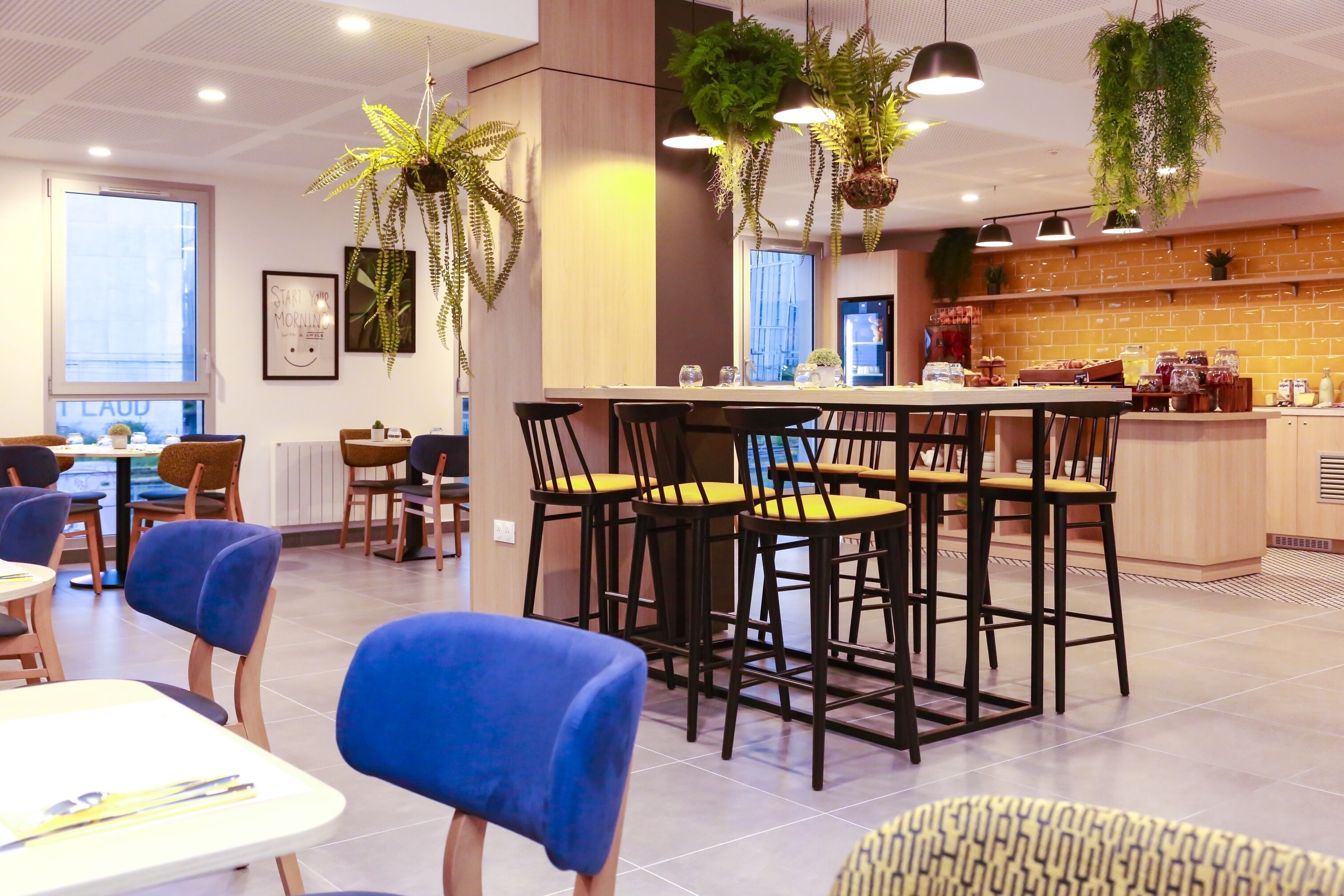 A modern dining area with a central island, black bar stools, and blue chairs.