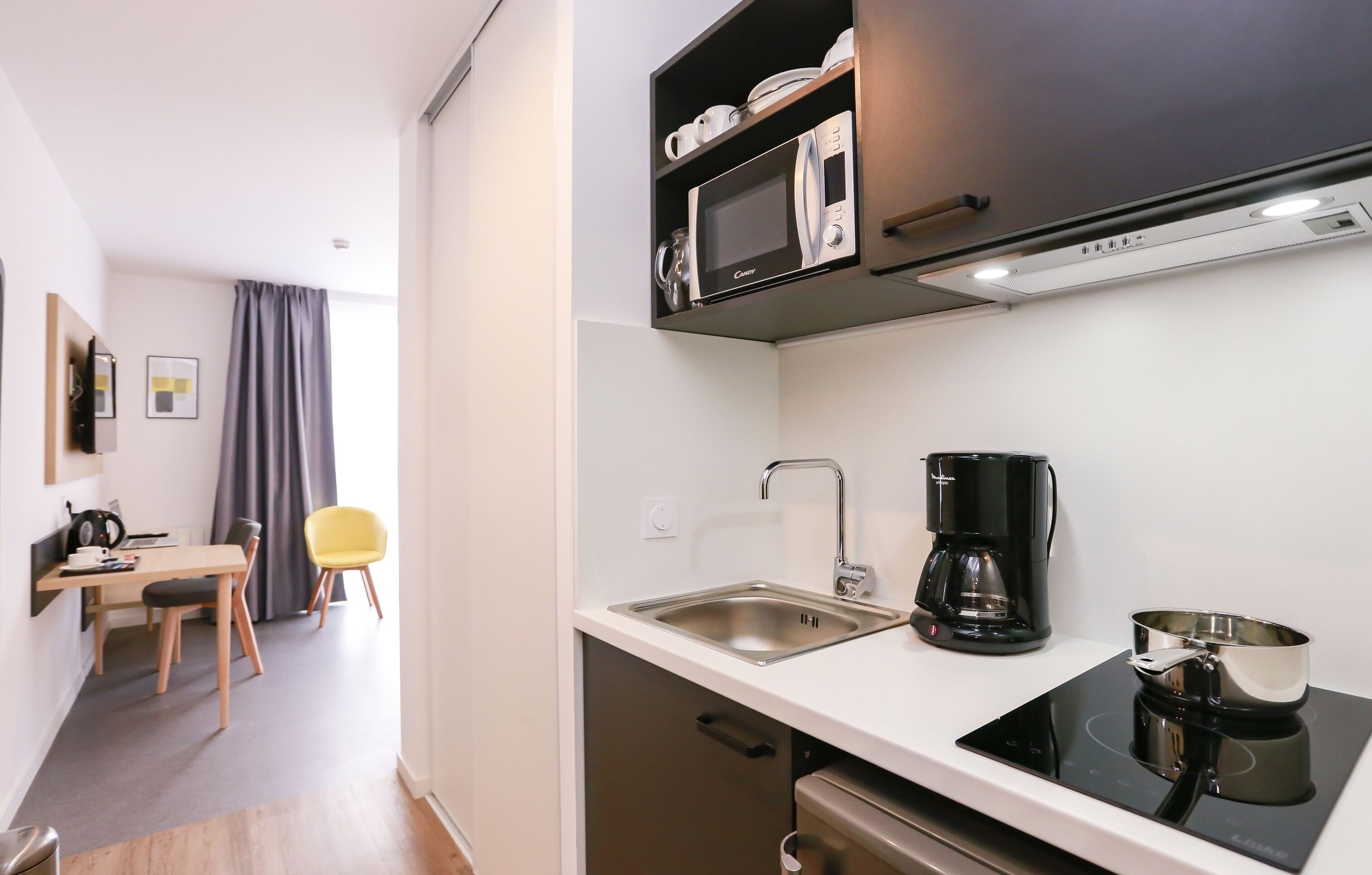 A compact kitchenette with a microwave, coffee maker, and a small stove.