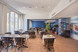 A spacious dining area with multiple tables and chairs, large windows, and a mural on the wall. - Appart Hotel Odalys City Marseille Centre Euromed (Marseille)