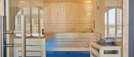 A sauna with wooden walls and a blue floor, featuring a bench and a small table with a basket.