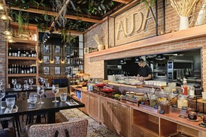 A restaurant with a brick wall, wooden counter, and hanging plants.