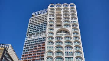 Un immeuble imposant, doté d’une architecture moderne, avec de nombreux balcons et une série de fenêtres en arc distinctives.