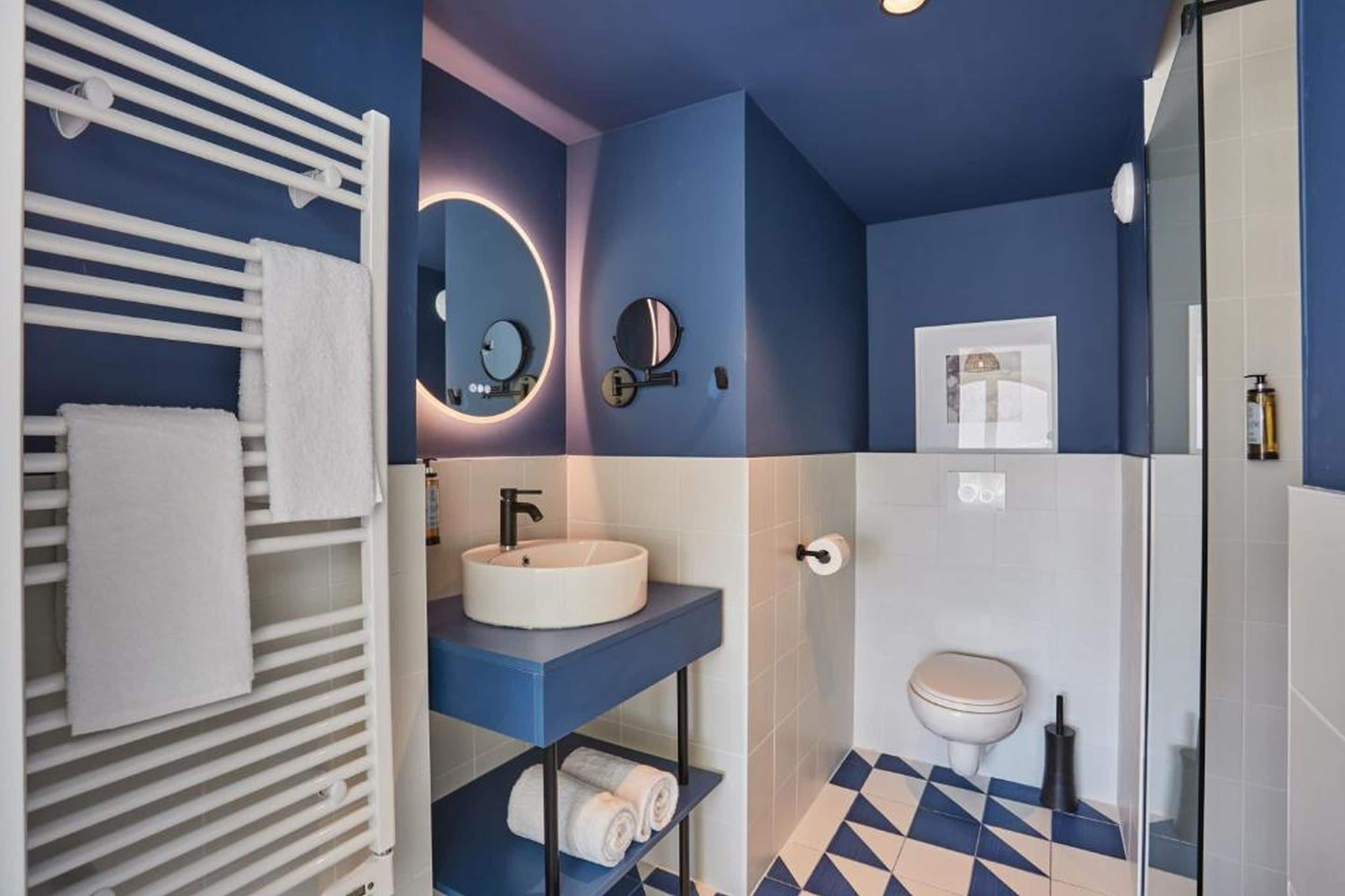 A modern bathroom with a white sink, a mirror, a toilet, and a shower area.