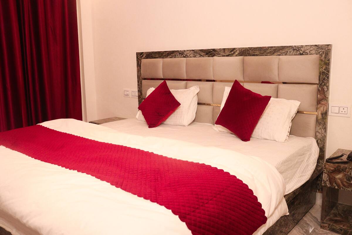 A bed with a red and white bedspread, two red pillows, and a marble headboard.