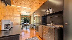A modern kitchen with wooden flooring, a coffee machine, and a built-in microwave. - Holzboxen Planneralm (Irdning-Donnersbachtal)