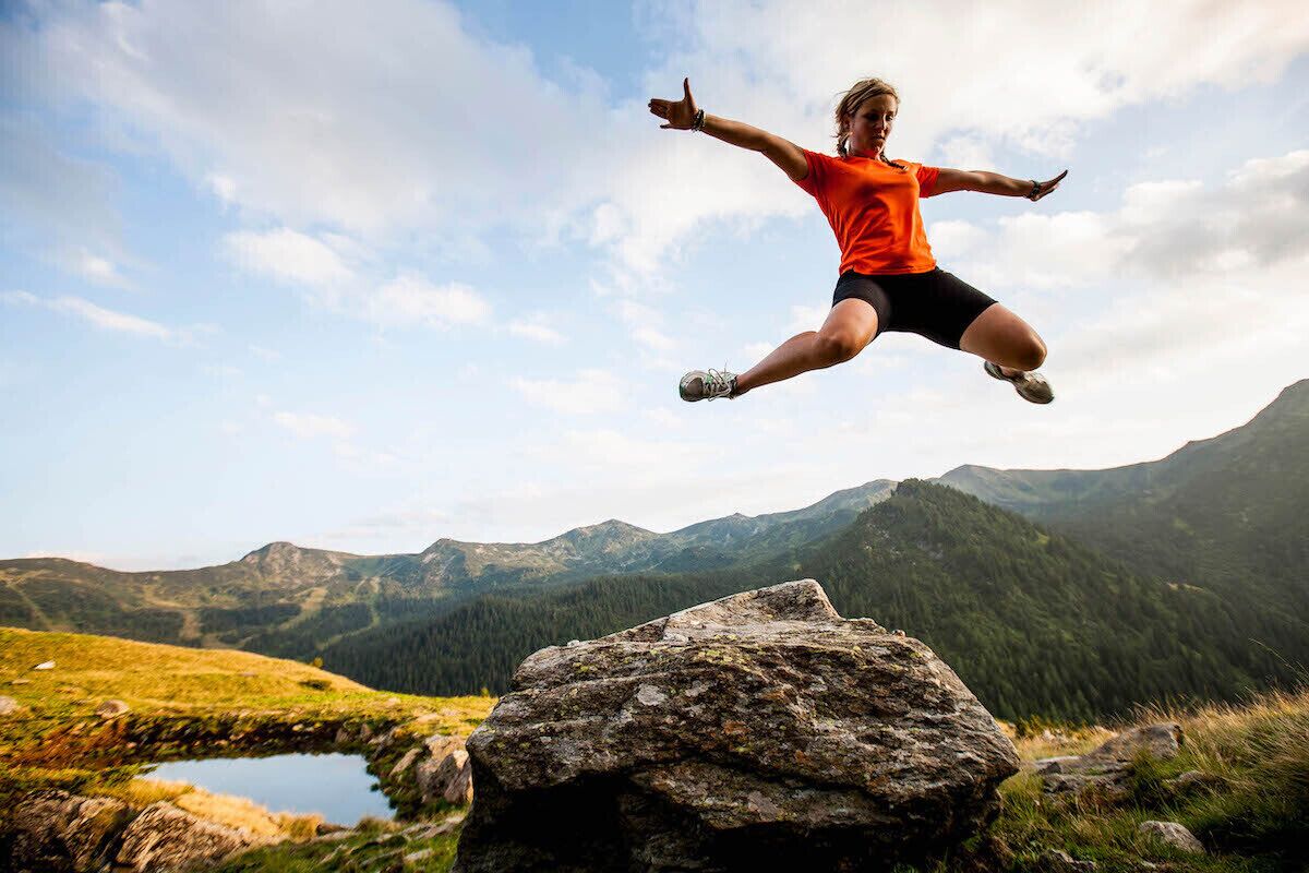 A person jumping in a mountainous landscape with a clear sky.