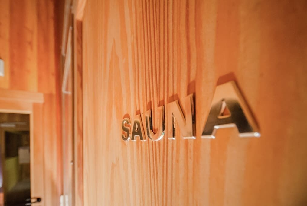 Paret de fusta amb la paraula 'SAUNA' en lletres metàl·liques.