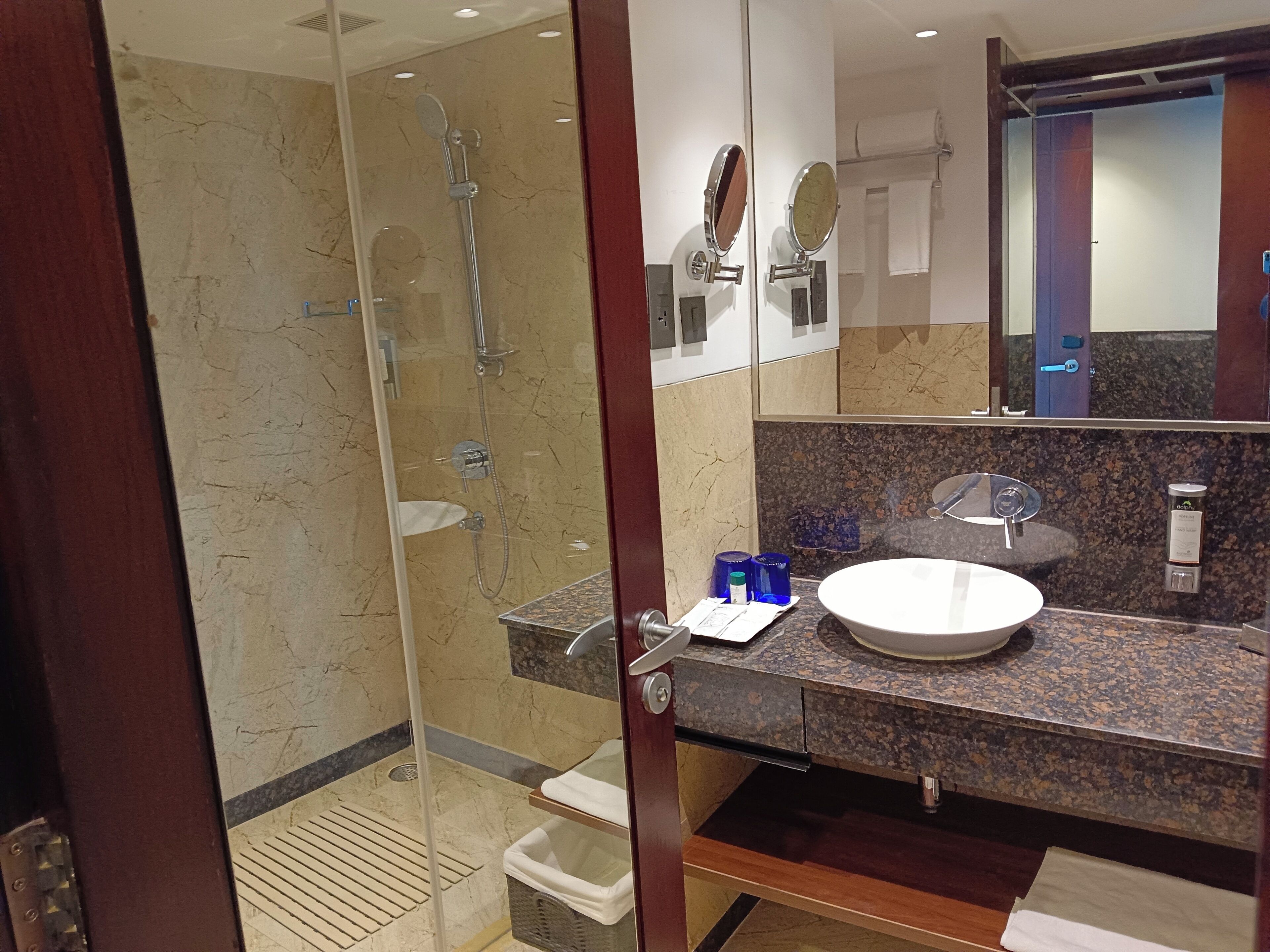 A modern bathroom with a glass-enclosed shower, a granite countertop, and a white sink.