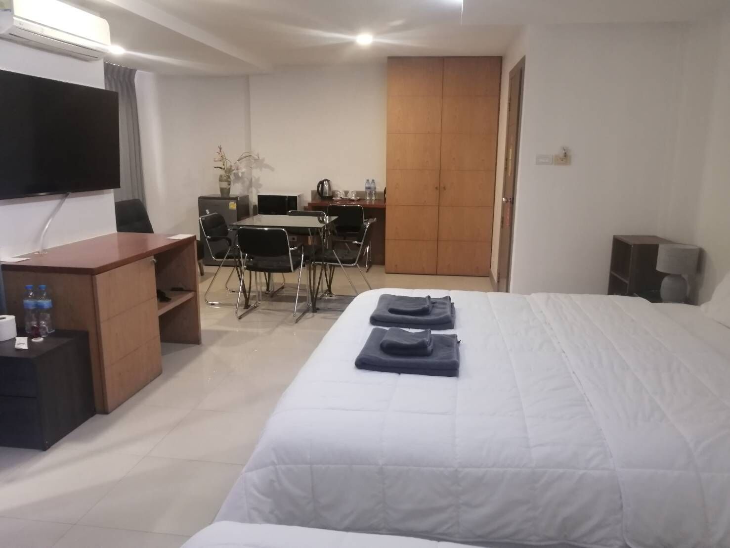 A hotel room with a bed, a desk, a chair, a TV, and a wardrobe.