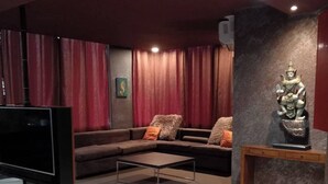 A modern living room with a flat-screen TV, a sofa, a coffee table, and a decorative statue. - Pasadena Lodge (Pattaya)