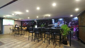 A restaurant with multiple tables and chairs, ceiling fans, and a projection screen. - Pasadena Lodge (Pattaya)