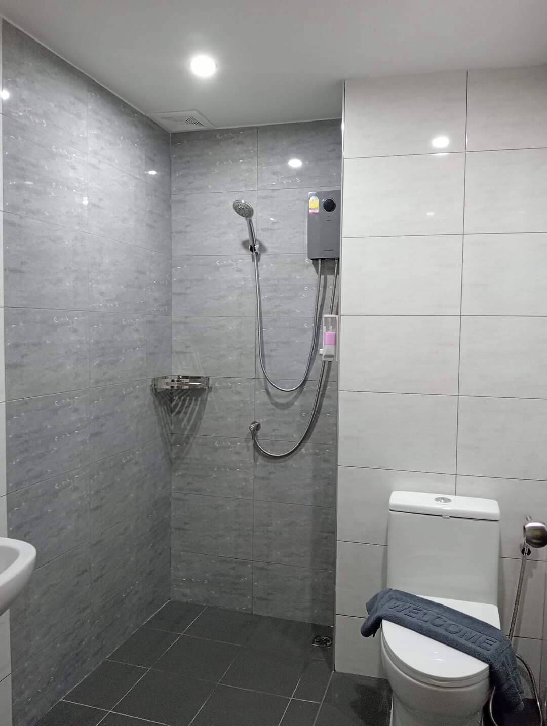 A modern bathroom with a shower, toilet, and a towel rack.