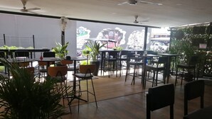An indoor dining area with tables and chairs, ceiling fans, and large windows. - Pasadena Lodge (Pattaya)
