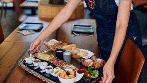 Un vassoio con assortiti prodotti alimentari, tra cui pasticcini, frutta e salse, su un tavolo di legno.