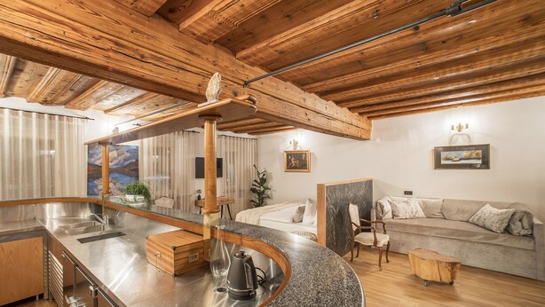 Una cucina moderna con un piano di lavoro in granito, elettrodomestici in acciaio inossidabile e travi in legno al soffitto.