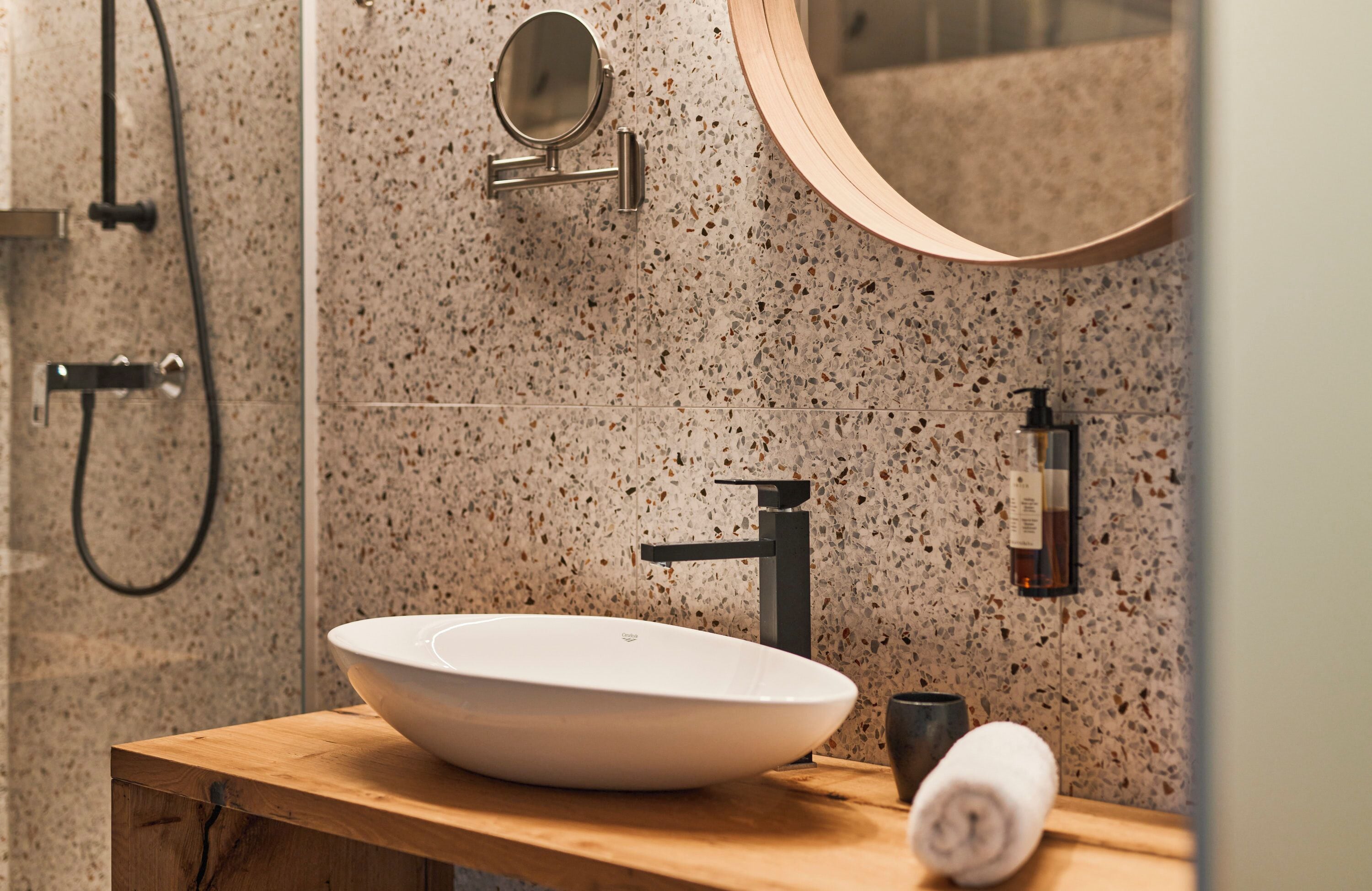 A bathroom with a freestanding sink, a handheld mirror, and a towel on the counter.