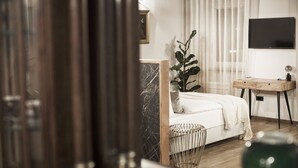 Una camera da letto con un letto, una scrivania, una pianta in vaso e un televisore appeso al muro.