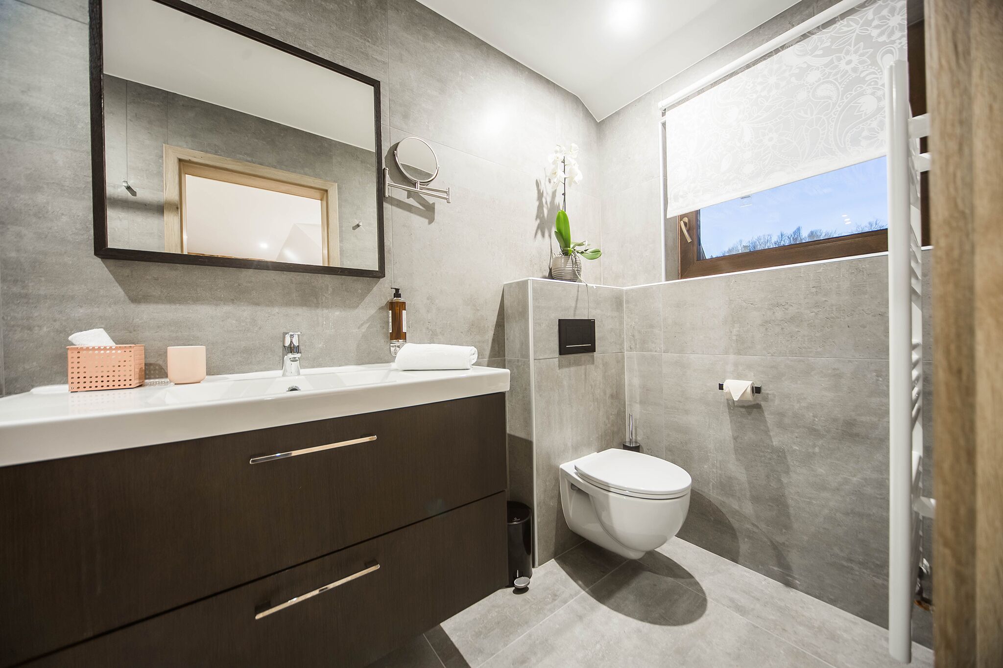 A modern bathroom with a large mirror, a toilet, and a shower area.