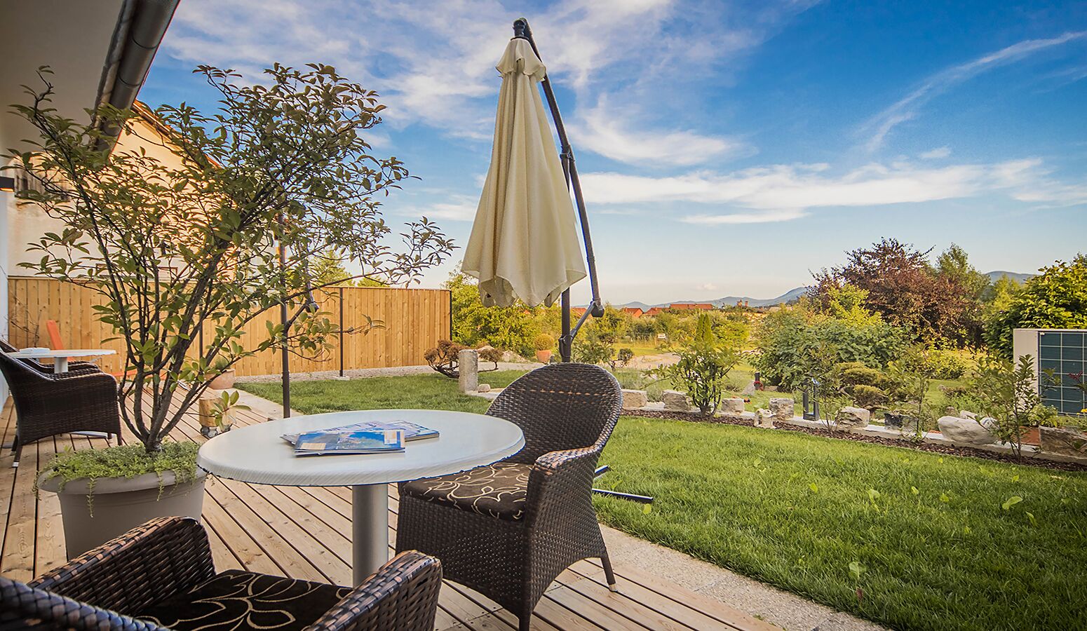 Une terrasse avec des meubles en osier, une table et une plante en pot.