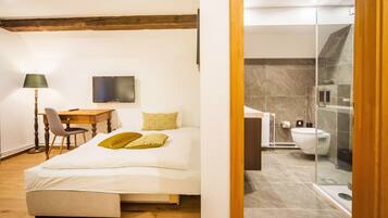 A bedroom with a bed, a desk, a chair, and a TV.