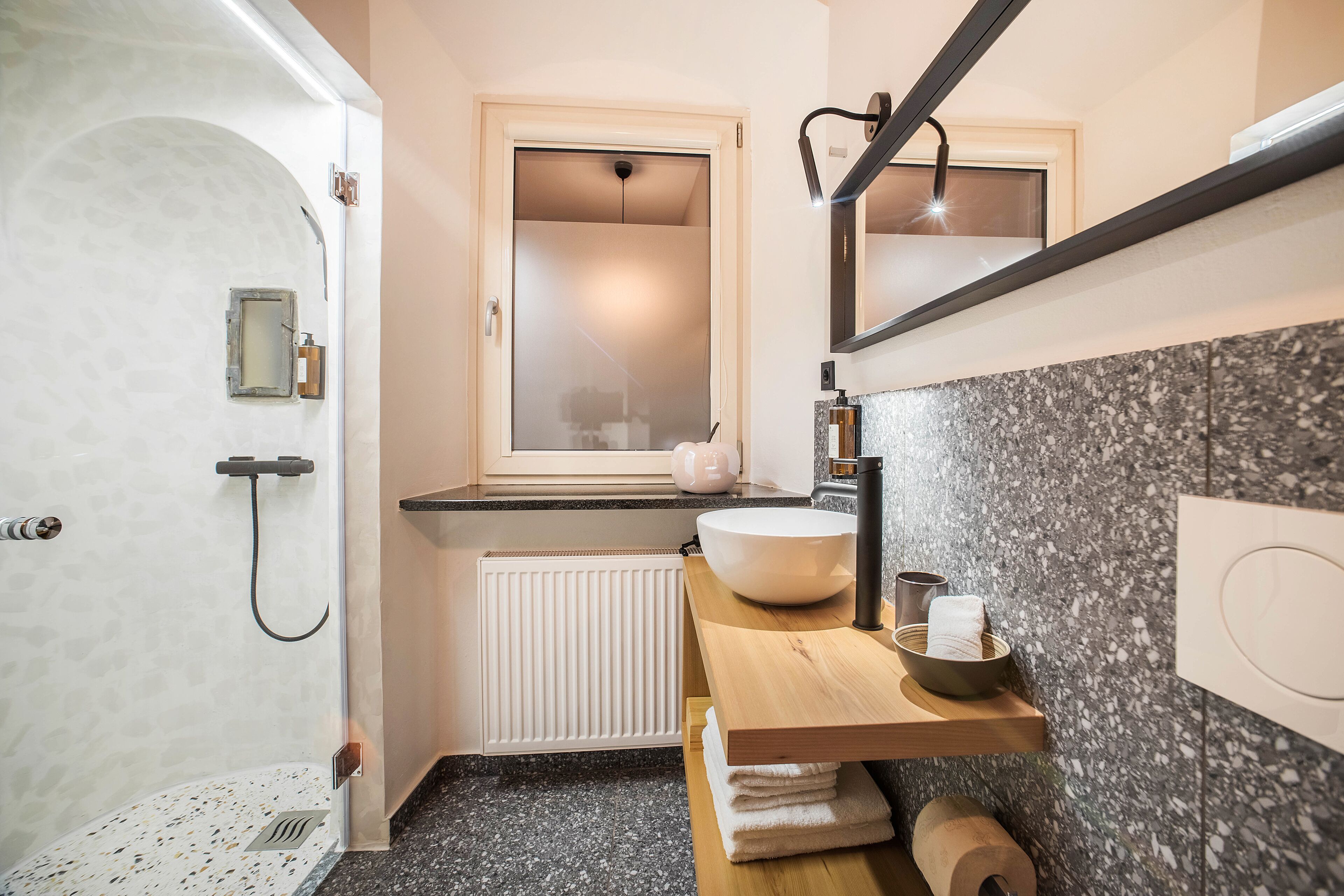 A modern bathroom with a freestanding bathtub, a large mirror, a vanity with a sink, and a towel rack.