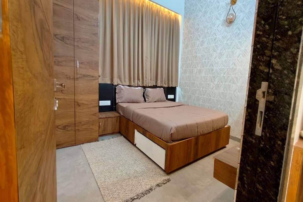 Une chambre à coucher avec un lit, une armoire en bois et un luminaire fixé au mur.