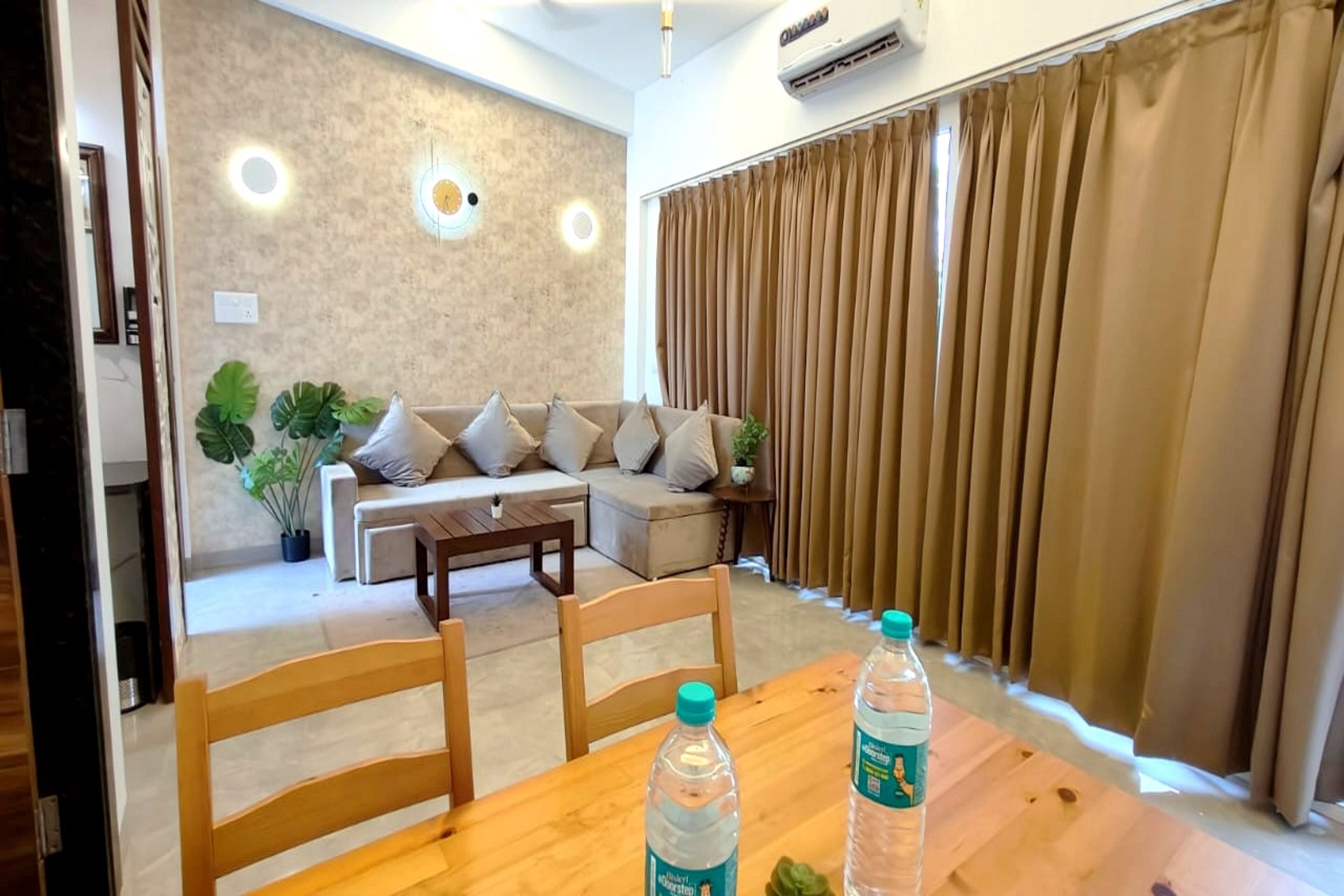 A modern living room with a sofa, a wooden coffee table, and two chairs. There are two bottles of water on the table.