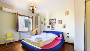 Une chambre à coucher avec un lit à courbes, une chaise et une fenêtre avec des volets.