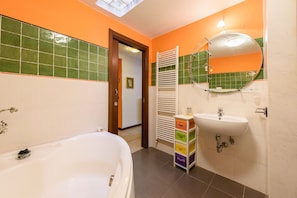 A bathroom with a bathtub, a sink, a mirror, and a towel rack. - Santa Croce's Vintage by Mmega (Florence)