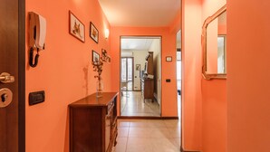 Un couloir aux murs orange, avec un meuble en bois, un téléphone et un miroir.