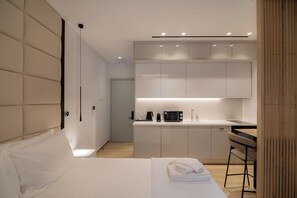 Una habitación de hotel moderna con cama, una kitchenette pequeña y una zona de comedor.