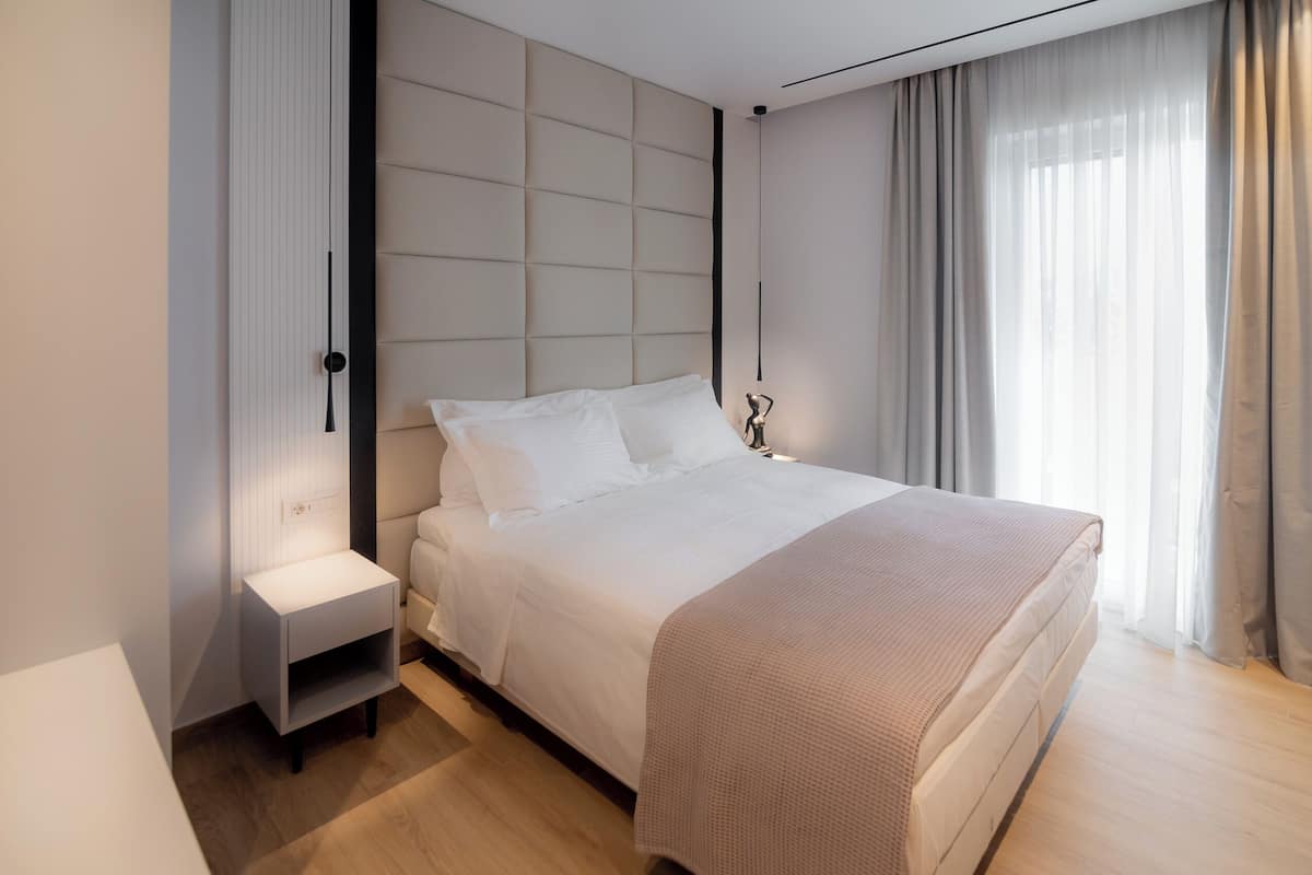 A modern bedroom with a large bed, a nightstand, and a bedside table.