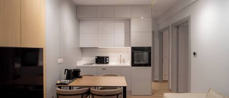 Una cocina moderna con comedor, microondas, máquina de café y sofá.