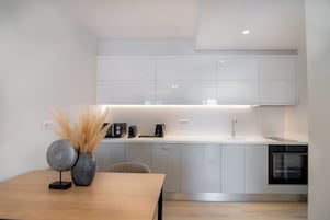 Una cucina moderna con mobili bianchi, un tavolo da pranzo in legno e un forno integrato.