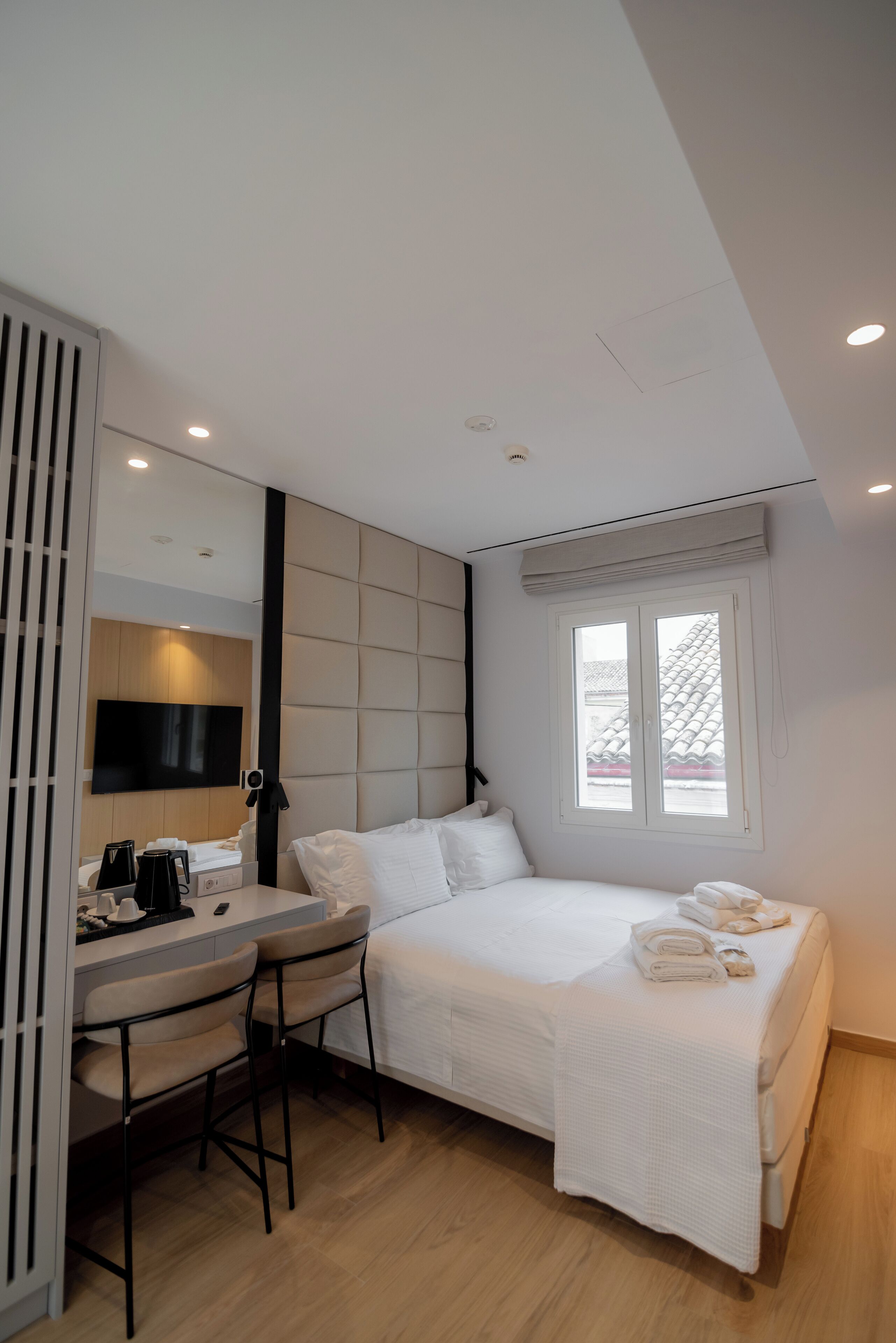 A modern hotel room with a bed, a desk, and a chair.